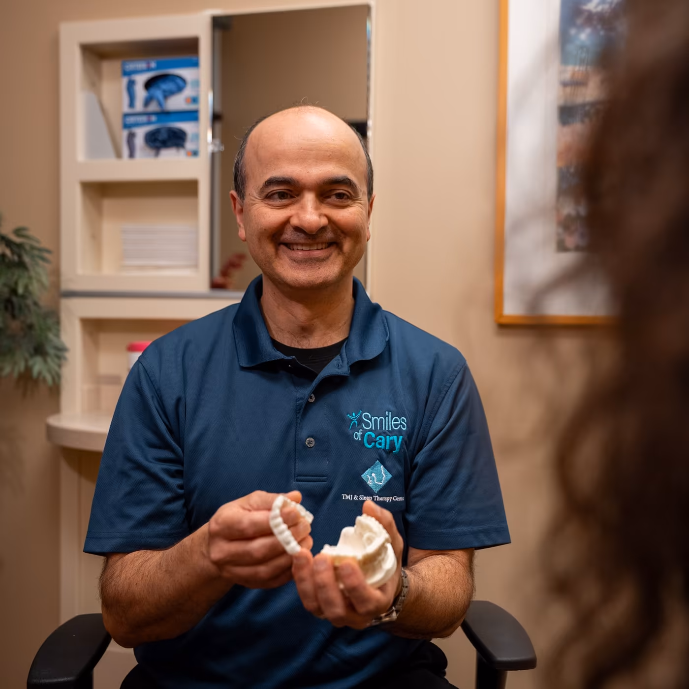 Dr. Charles Ferzli holding dental bite models in a consultation room at Smiles of Cary