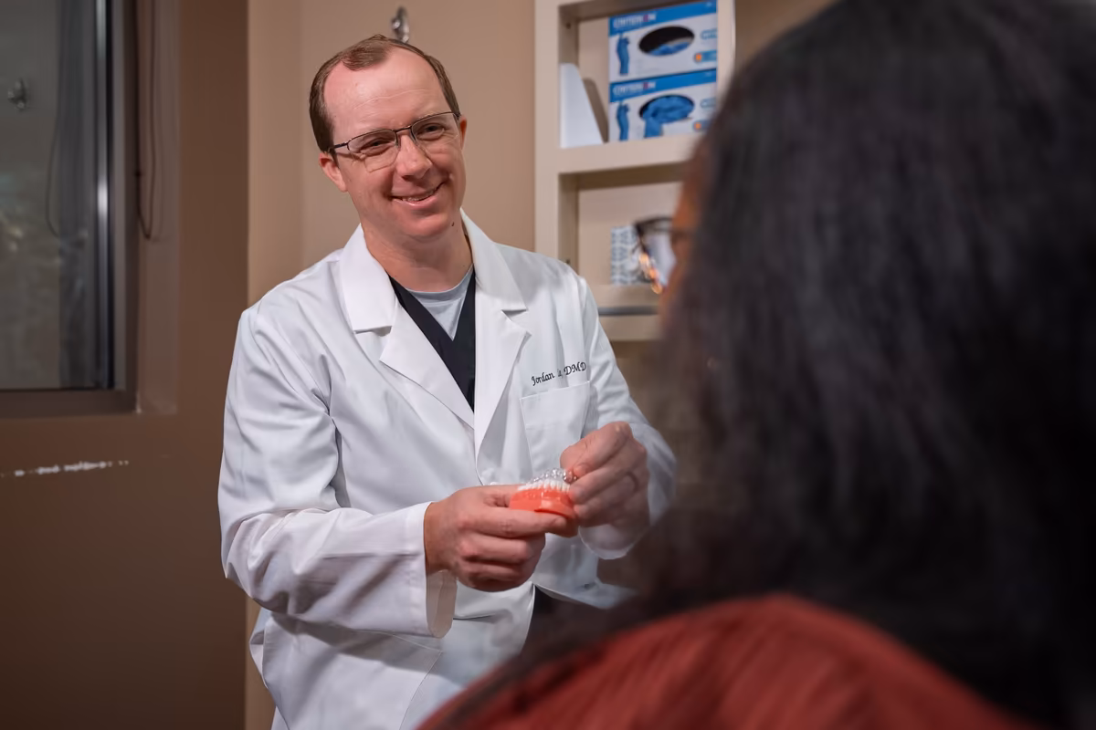 Dr. Jordan Lee holding up a dental model to explain treatment at Smiles of Cary