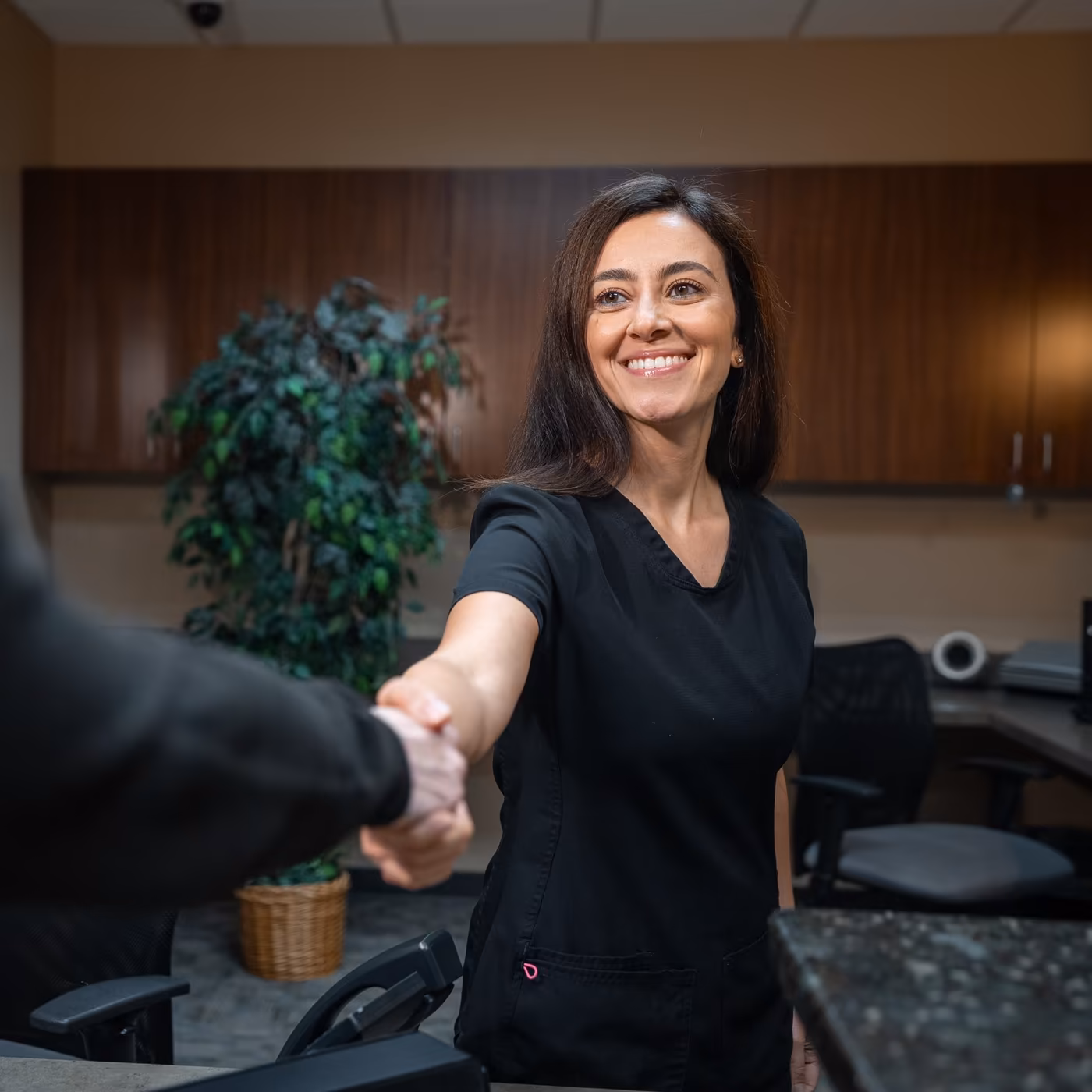 A team member shaking a patient's hand at the front desk of Smiles of Cary