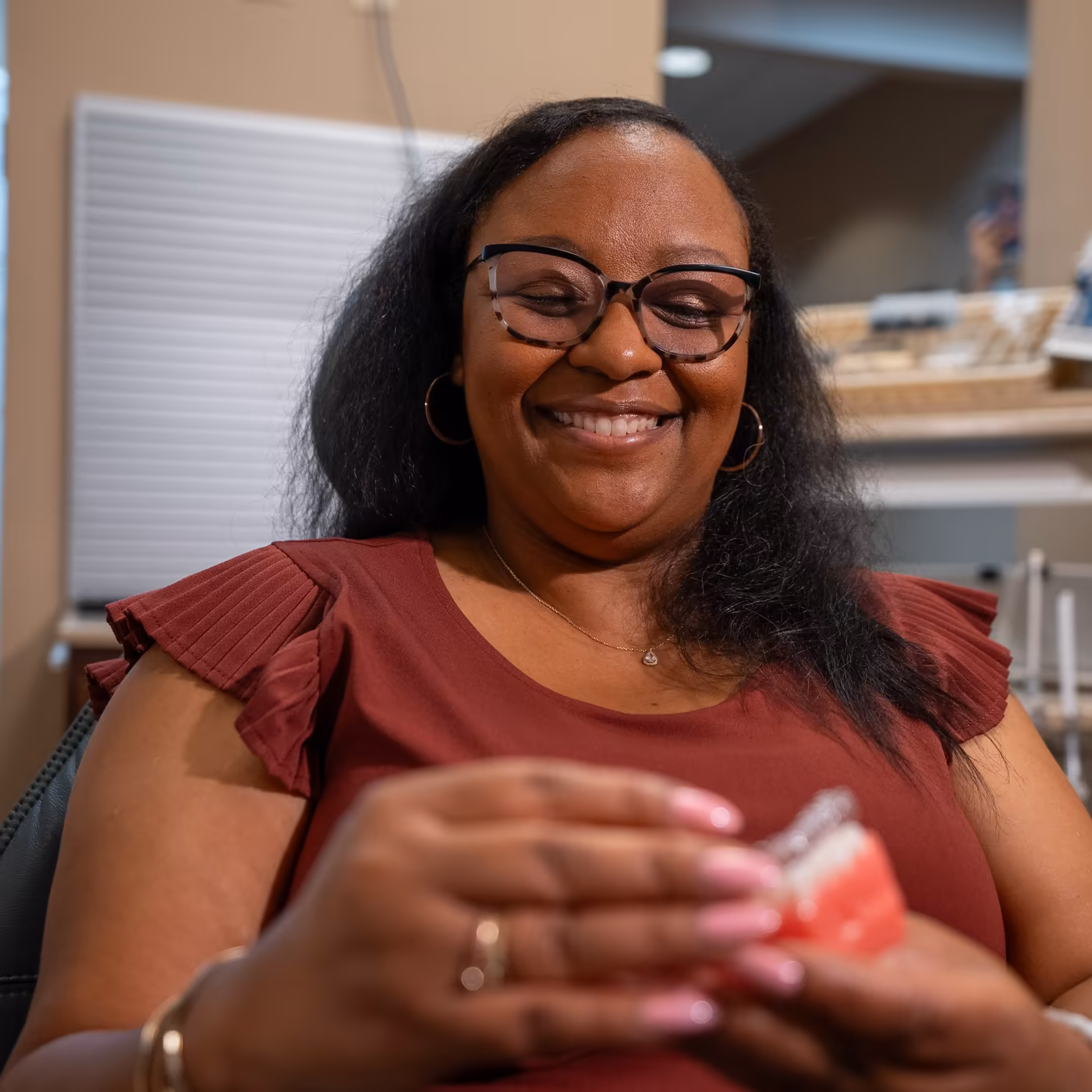 A patient holding a dental model with a clear aligner during her consultation at Smiles of Cary